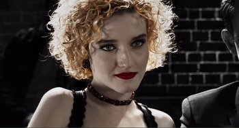 Movie still from “Sin City: A Dame to Kill For” (2014), directed by Frank Miller – A person with curly hair wearing a necklace; Close Up shot, Low angle