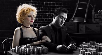 Movie still from “Sin City: A Dame to Kill For” (2014), directed by Frank Miller – A man and a woman sitting at a table with stacks of coins in front of them; Medium shot, Low angle
