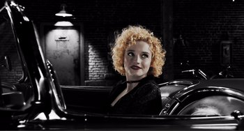 Movie still from “Sin City: A Dame to Kill For” (2014), directed by Frank Miller – A woman sitting in the back of an old car; Medium shot, High angle