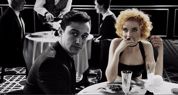 Movie still from “Sin City: A Dame to Kill For” (2014), directed by Frank Miller – A man and a woman sitting at a dinner table; Medium shot, High angle