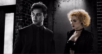 Movie still from “Sin City: A Dame to Kill For” (2014), directed by Frank Miller – A man and a woman standing next to each other in front of a brick wall; Medium shot, Low angle