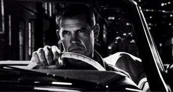Movie still from “Sin City: A Dame to Kill For” (2014), directed by Frank Miller – A black - and - white photo of a man driving a car; Close Up shot, Low angle