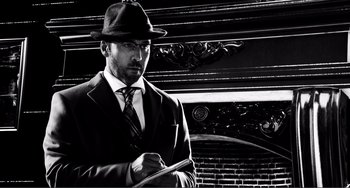 Movie still from “Sin City: A Dame to Kill For” (2014), directed by Frank Miller – A black and white photo of a man in a suit and hat; Close Up shot, Low angle