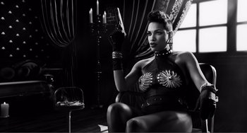 Movie still from “Sin City: A Dame to Kill For” (2014), directed by Frank Miller – A black and white photo of a woman holding a knife in her right hand; Medium shot, Low angle