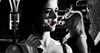 Movie still from “Sin City: A Dame to Kill For” (2014), directed by Frank Miller – A black and white photo of a woman smoking a cigarette; Close Up shot, Low angle