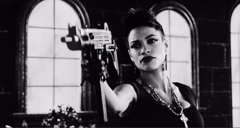 Movie still from “Sin City: A Dame to Kill For” (2014), directed by Frank Miller – A black and white photo of a woman holding a gun; Close Up shot, Low angle