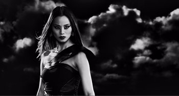 Movie still from “Sin City: A Dame to Kill For” (2014), directed by Frank Miller – Black and white photograph of a woman in front of a cloudy sky; Close Up shot, Low angle
