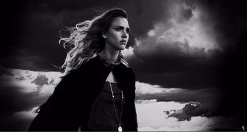 Movie still from “Sin City: A Dame to Kill For” (2014), directed by Frank Miller – Black and white photograph of a woman in front of a cloudy sky; Close Up shot, Low angle