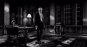 Movie still from “Sin City: A Dame to Kill For” (2014), directed by Frank Miller – An older man in a suit standing in a room; Wide shot, Low angle