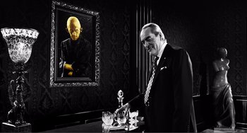 Movie still from “Sin City: A Dame to Kill For” (2014), directed by Frank Miller – A black and white photo of a man standing next to a painting; Medium shot, Low angle