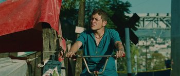 Movie still from “Sin Nombre” (2009), directed by Cary Joji Fukunaga – A person riding a bike on top of a dirt road; Medium shot, Low angle
