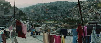 Movie still from “Sin Nombre” (2009), directed by Cary Joji Fukunaga – Two women sit on a ledge with a view of a city; Extreme Wide shot, High angle