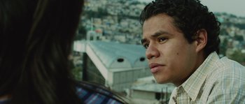 Movie still from “Sin Nombre” (2009), directed by Cary Joji Fukunaga – A young man looking into the distance while standing on a balcony; Close Up shot, Over the shoulder angle