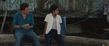 Movie still from “Sin Nombre” (2009), directed by Cary Joji Fukunaga – A young boy sitting on a tree trunk; Medium shot, Over the shoulder angle