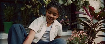 Movie still from “Sin Nombre” (2009), directed by Cary Joji Fukunaga – A young boy sitting on the ground next to a plant; Medium shot, High angle
