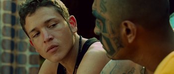 Movie still from “Sin Nombre” (2009), directed by Cary Joji Fukunaga – A man with a tattoo on his face and a man with a tattoo on his neck; Close Up shot, Over the shoulder angle