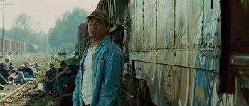 Movie still from “Sin Nombre” (2009), directed by Cary Joji Fukunaga – A man standing in front of a train car; Medium shot, Low angle