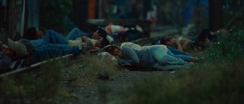 Movie still from “Sin Nombre” (2009), directed by Cary Joji Fukunaga – A group of people laying down on the ground; Wide shot, High angle