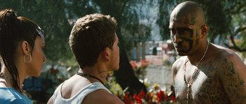 Movie still from “Sin Nombre” (2009), directed by Cary Joji Fukunaga – A man in a white tank top is talking to another man in a white tank top; Close Up shot, Over the shoulder angle