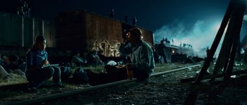 Movie still from “Sin Nombre” (2009), directed by Cary Joji Fukunaga – A man sitting on the side of the road eating a sandwich; Wide shot, High angle