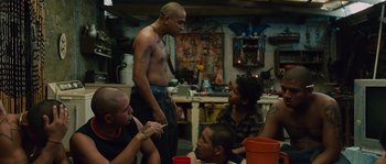 Movie still from “Sin Nombre” (2009), directed by Cary Joji Fukunaga – A group of men sitting around a table; Medium shot, Over the shoulder angle