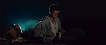 Movie still from “Sin Nombre” (2009), directed by Cary Joji Fukunaga – A man sitting on a bed with a knife in his hand; Medium shot, Low angle