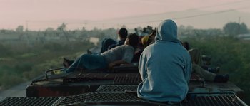 Movie still from “Sin Nombre” (2009), directed by Cary Joji Fukunaga – A group of people sitting on top of a bench; Medium shot, Low angle