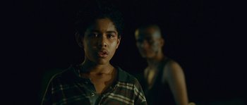 Movie still from “Sin Nombre” (2009), directed by Cary Joji Fukunaga – A young man standing next to another young man; Close Up shot, Over the shoulder angle