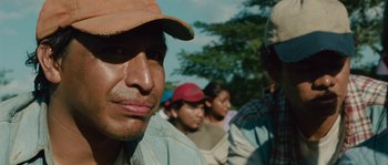 Movie still from “Sin Nombre” (2009), directed by Cary Joji Fukunaga – A group of people standing next to each other on a field; Close Up shot, Low angle