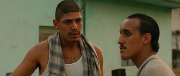 Movie still from “Sin Nombre” (2009), directed by Cary Joji Fukunaga – A man with a tattoo on his chest looks at himself in the mirror; Close Up shot, Over the shoulder angle