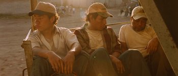 Movie still from “Sin Nombre” (2009), directed by Cary Joji Fukunaga – A group of men sitting next to each other on a field; Medium shot, High angle