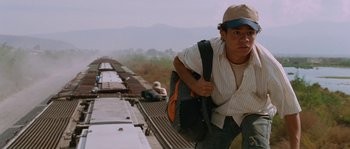 Movie still from “Sin Nombre” (2009), directed by Cary Joji Fukunaga – A man is standing on the side of a train; Medium shot, Low angle