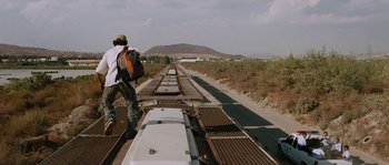 Movie still from “Sin Nombre” (2009), directed by Cary Joji Fukunaga – A man standing on the side of a train tracks; Wide shot, Low angle