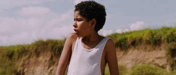 Movie still from “Sin Nombre” (2009), directed by Cary Joji Fukunaga – A young boy in a white tank top looking to his left; Close Up shot, Low angle