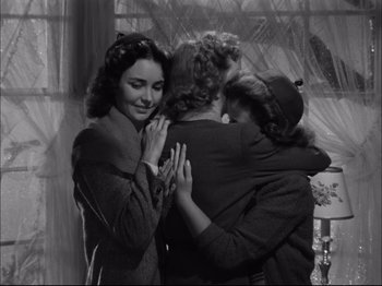 Movie still from “Since You Went Away” (1944), directed by John Cromwell – A group of people hugging each other in front of a window; Medium shot, High angle