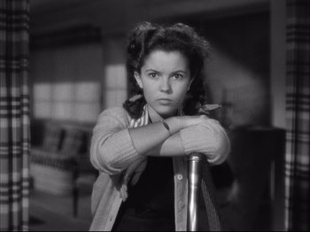Movie still from “Since You Went Away” (1944), directed by John Cromwell – A young woman leaning on a pole in a living room; Close Up shot, High angle