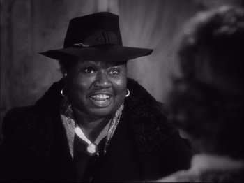 Movie still from “Since You Went Away” (1944), directed by John Cromwell – An older black woman wearing a hat and a jacket; Close Up shot, Over the shoulder angle
