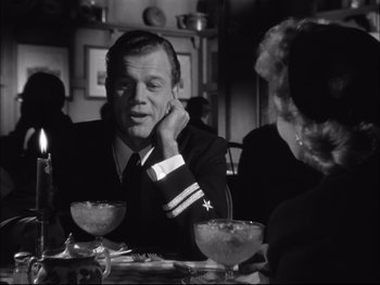 Movie still from “Since You Went Away” (1944), directed by John Cromwell – A man sitting at a table with two other people; Medium shot, Over the shoulder angle