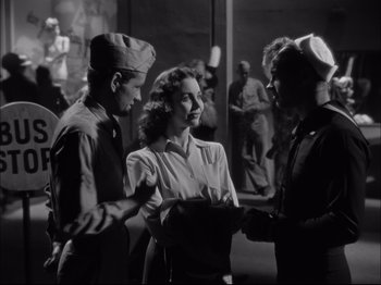 Movie still from “Since You Went Away” (1944), directed by John Cromwell – A group of men standing around a woman in a room; Medium shot, Over the shoulder angle