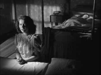 Movie still from “Since You Went Away” (1944), directed by John Cromwell – A woman sitting on a bed next to a person sleeping; Medium shot, Low angle