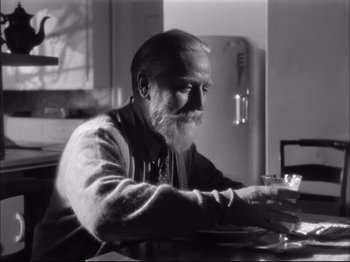 Movie still from “Since You Went Away” (1944), directed by John Cromwell – An older man sitting at a table in front of a refrigerator; Medium shot, Low angle