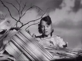 Movie still from “Since You Went Away” (1944), directed by John Cromwell – An old photo of a woman looking at a pile of papers; Medium shot, Low angle