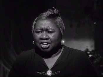 Movie still from “Since You Went Away” (1944), directed by John Cromwell – An older black woman is looking at the camera; Close Up shot, High angle