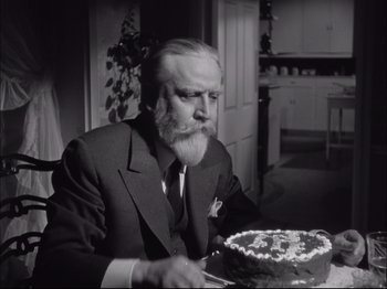 Movie still from “Since You Went Away” (1944), directed by John Cromwell – An older man sitting at a table with a cake in front of him; Close Up shot, High angle