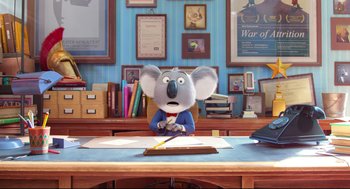 Movie still from “Sing” (2016), directed by Christophe Lourdelet – A koala is sitting at a desk with a pencil in his mouth; Medium shot, High angle