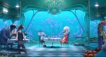 Movie still from “Sing” (2016), directed by Christophe Lourdelet – A couple of people sitting at a table in front of an aquarium; Wide shot, High angle