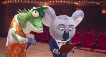 Movie still from “Sing” (2016), directed by Christophe Lourdelet – A cartoon of a dinosaur and a koala in front of an audience; Medium shot, Over the shoulder angle