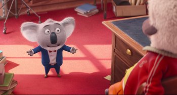 Movie still from “Sing” (2016), directed by Christophe Lourdelet – A koala is standing in front of a desk; Wide shot, Over the shoulder angle