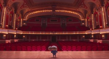 Movie still from “Sing” (2016), directed by Christophe Lourdelet – A person standing in front of an empty stage; Extreme Wide shot, Low angle