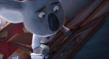 Movie still from “Sing” (2016), directed by Christophe Lourdelet – A stuffed koala is standing in front of a table; Medium shot, High angle
